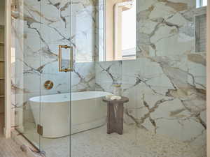 Full bath featuring a freestanding bath, tile patterned floors, and a marble finish shower