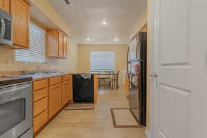 Kitchen featuring visible vents, a sink, light wood-style floors, a wealth of natural light, and black appliances