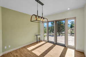 Unfurnished dining area with recessed lighting, a notable chandelier, baseboards, and wood finished floors