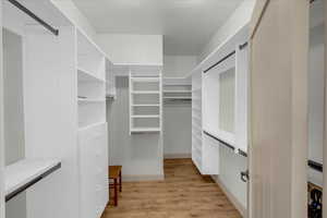Walk in closet with light wood-style flooring