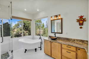 Bathroom with vanity, recessed lighting, a freestanding bath, a stall shower, and tile patterned floors