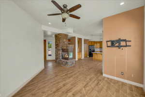 Unfurnished living room with light wood finished floors, baseboards, a ceiling fan, and a fireplace
