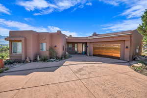 Adobe home featuring concrete driveway, stucco siding, a tiled roof, and an attached garage
