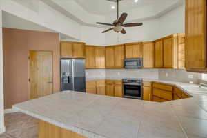 Kitchen with a high ceiling, a sink, backsplash, and stainless steel appliances