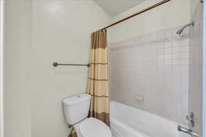 Full bath with toilet and shower / bathtub combination with curtain