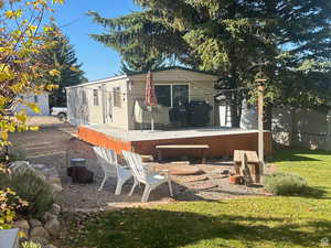 Back of house with fence, a wooden deck, and a lawn
