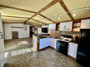 Kitchen with gas stove, lofted ceiling with beams, freestanding refrigerator, open shelves, and dark countertops