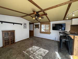 Unfurnished living room with baseboards, a ceiling fan, carpet flooring, and lofted ceiling with beams