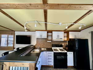 Kitchen featuring open shelves, a sink, under cabinet range hood, black appliances, and white cabinetry