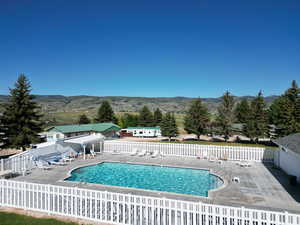 Community pool with a mountain view, fence, and a patio