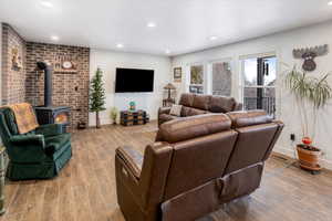 Living room with baseboards, wood finished floors, a wood stove, and recessed lighting