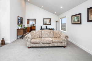 Carpeted living room featuring baseboards, high vaulted ceiling, and recessed lighting