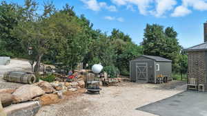 View of yard featuring a fire pit, a storage unit, and view of wooded area