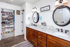 Bathroom featuring double vanity, a sink, visible vents, and wood tiled floor