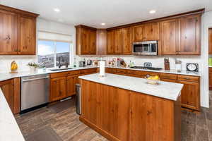 Kitchen featuring backsplash, a kitchen island, a sink, appliances with stainless steel finishes, and brown cabinets