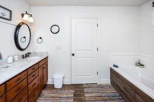 Bathroom with a bath, baseboards, and vanity