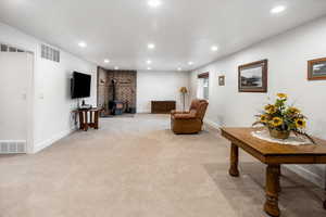 Sitting room featuring visible vents, a wood stove, recessed lighting, and light colored carpet