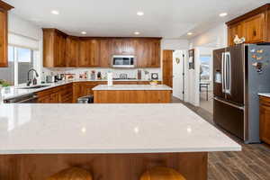 Kitchen with a sink, decorative backsplash, appliances with stainless steel finishes, and dark wood-style floors