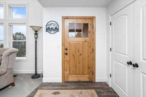 Entrance foyer with baseboards, wood tiled floor, and dark colored carpet