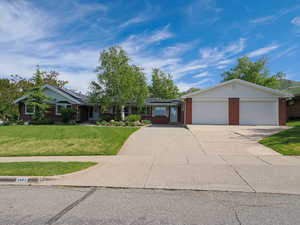 Single story home featuring a front yard, brick siding, roof mounted solar panels, concrete driveway, and an attached garage
