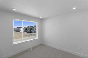 Spare room with visible vents, baseboards, recessed lighting, and light carpet
