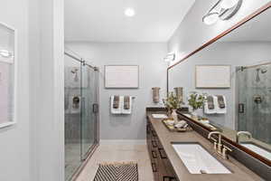 Bathroom featuring a sink, double vanity, and a stall shower