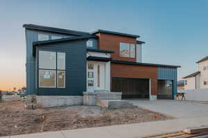 Contemporary house featuring an attached garage, fence, and concrete driveway