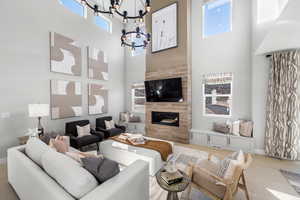 Living area with a chandelier, a high ceiling, wood finished floors, and a tiled fireplace