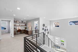 Interior space with visible vents, light colored carpet, an upstairs landing, and recessed lighting