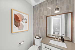 Bathroom with vanity, visible vents, tile walls, and toilet