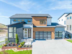 Contemporary house with an attached garage, roof with shingles, board and batten siding, and concrete driveway