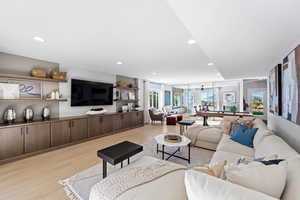 Living area with light wood-type flooring and recessed lighting