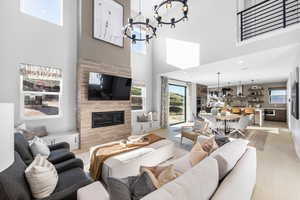 Living area featuring an inviting chandelier, a fireplace, light wood-style flooring, recessed lighting, and a high ceiling