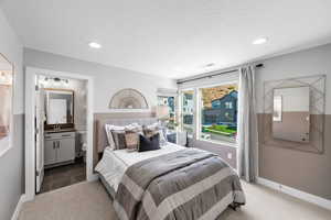 Carpeted bedroom with recessed lighting, ensuite bath, visible vents, and a sink