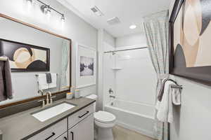 Full bathroom featuring shower / tub combo, vanity, tile patterned floors, toilet, and visible vents