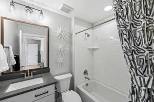 Bathroom featuring toilet, vanity, shower / tub combo with curtain, and visible vents