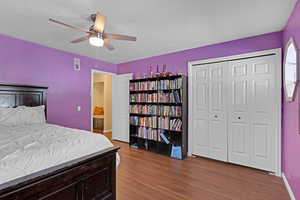 Bedroom with a textured ceiling, a ceiling fan, visible vents, baseboards, and dark wood-style floors