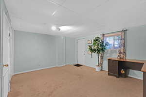 Interior space featuring carpet flooring, a paneled ceiling, and baseboards