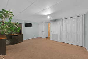 Unfurnished bedroom featuring visible vents, baseboards, a drop ceiling, and carpet