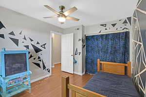 Bedroom featuring wood finished floors, ceiling fan, baseboards, and visible vents