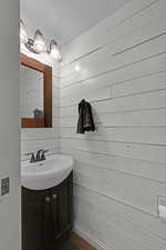 Bathroom featuring wood walls, vanity, and a textured ceiling