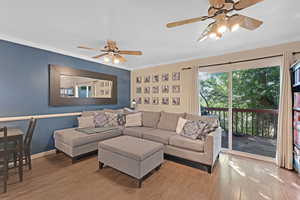 Living room with a textured ceiling, a ceiling fan, crown molding, and wood finished floors