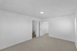 Unfurnished bedroom with light colored carpet, recessed lighting, ensuite bath, and baseboards