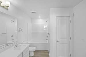 Bathroom with visible vents, bathing tub / shower combination, wood finished floors, and vanity