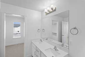 Bathroom with baseboards, a textured ceiling, double vanity, and a sink