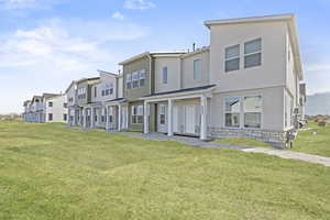 Townhome / multi-family property featuring a residential view, a front lawn, and stone siding