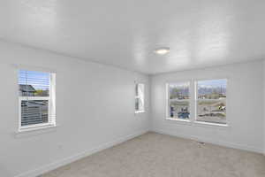 Spare room with a textured ceiling, visible vents, light carpet, and baseboards