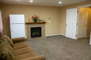 Carpeted living room featuring a fireplace, baseboards, and recessed lighting