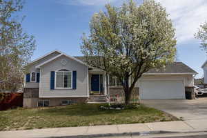 View of front of house featuring an attached garage, driveway, and a front lawn