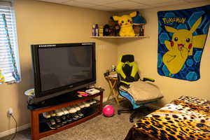 Bedroom featuring baseboards, a drop ceiling, and carpet